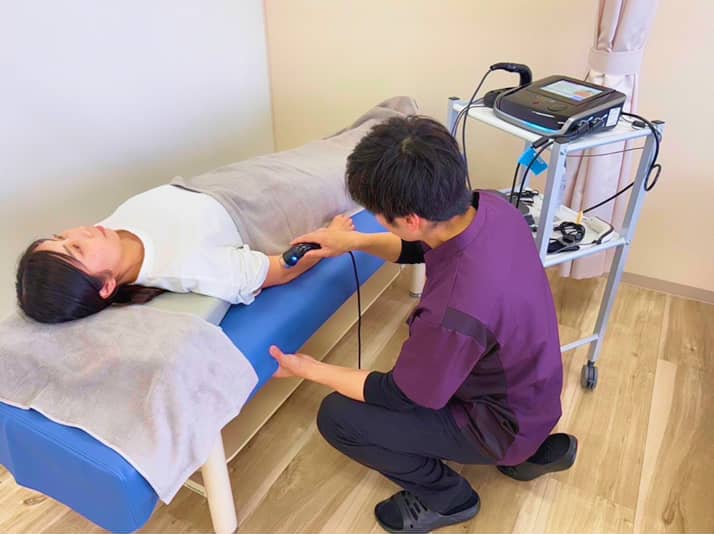 患者に施術機器を使用して治療する様子
